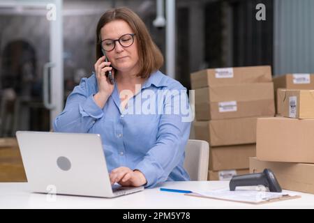 dropshipping, femme avec ordinateur portable bureau parlant téléphone boîtes d'expédition, vente au détail e-commerce Banque D'Images