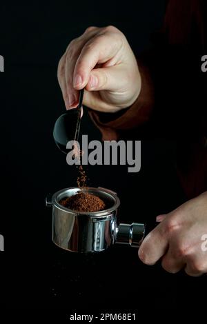 le barista verse le café moulu dans le porte-filtre à café Banque D'Images