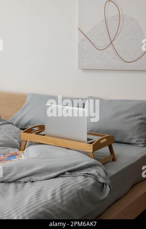 Plateau table en bois avec ordinateur portable et smartphone sur le lit à l'intérieur Banque D'Images