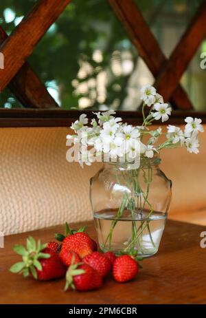 Fraises fraîches et bouquet de belles fleurs blanches sur table en bois Banque D'Images