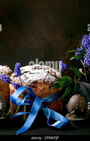 Gâteau traditionnel de Pâques maison aux panettons avec œufs noirs colorés, fleurs de muscari fleuries sur une table en bois noir. Pâtisserie italienne traditionnelle de Pâques, Banque D'Images