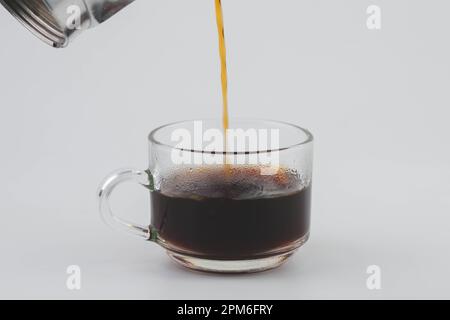 Verser le café de la marmite dans un verre transparent isolé sur fond blanc. Gros plan sur le café filtre fraîchement préparé dans une tasse. PréEPAR Banque D'Images