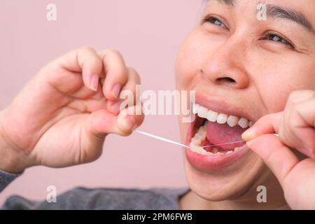 Gros plan sur une femme asiatique souriante et nettoyage pour un sourire parfait. Dents blanches saines par le fil dentaire, la santé bucco-dentaire et les soins dentaires. Banque D'Images