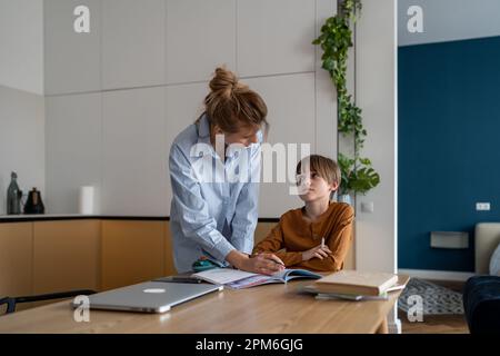Une femme enseignante ou un tuteur expliquant le matériel d'apprentissage à l'enfant pendant la leçon privée Banque D'Images