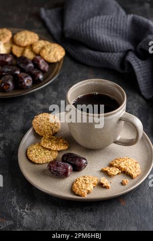 Une tasse de café sur une assiette avec des dattes et des biscuits aux céréales. Banque D'Images