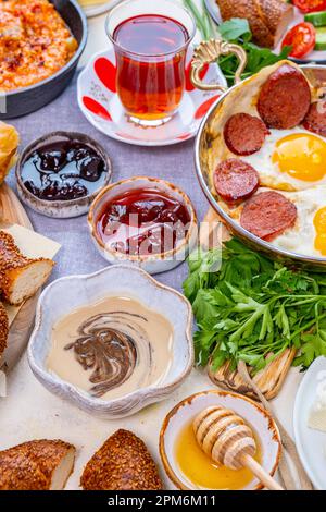 Tahin pekmez dans un bol et d'autres aliments turcs pour le petit-déjeuner comme des confitures, des œufs et du sujuk, des menemen et du thé turc. Banque D'Images