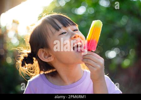 Mignon bébé fille heureux manger de glace popsicle en été. Image pour le concept de sucré, de graisse, d'obésité et de diabète chez les enfants. Banque D'Images