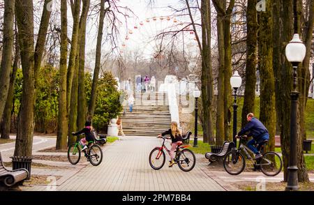 Bonne famille au printemps dans le parc. Les gens marchent dans le parc avec la toile de fond des escaliers et une grande roue .9 avril 2023 Biélorussie, Minsk Banque D'Images