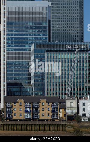 Les gratte-ciel de Canary Wharf, qui font partie du quartier central des affaires de Londres, dominent les anciens logements au bord de la Tamise au premier plan Banque D'Images