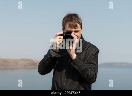 Jeune homme avec un appareil photo. À l'extérieur. Mise au point sélective. Banque D'Images
