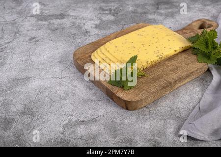 Fromage hollandais avec orties sur une planche en bois Banque D'Images