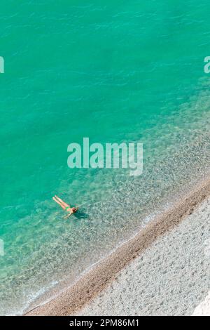 France, Seine-Maritime, pays de Caux, Côte d'Albâtre, Etretat, falaise d'Amont, vue d'une femme portant un bikini, bain rafraîchissant dans une mer turquoise et transparente, au bord de la plage de galets Banque D'Images