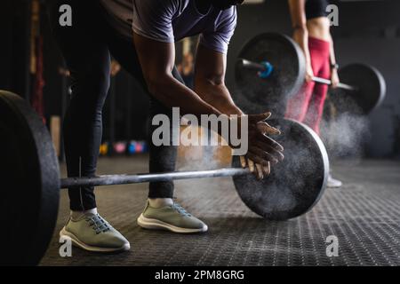 Coupe basse de jeune homme biracial se claquant les mains avec de la poudre de talc et se préparant à l'entraînement Banque D'Images