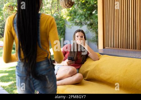 Triste adolescents divers amis assis sur un canapé et utilisant un smartphone Banque D'Images
