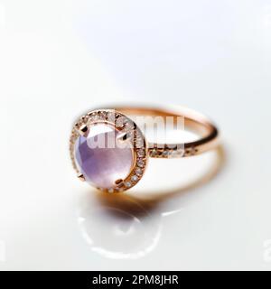Un beau diamant d'or et un anneau améthyste reposant sur une surface blanche. Banque D'Images
