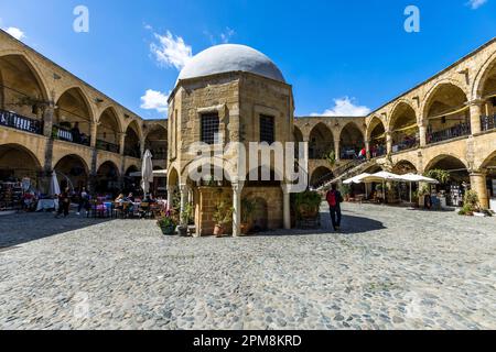 Le Büyük Han (Grande Auberge), la plus grande caravanserai de Chypre, entoure sa cour autour d'une salle de prière octogonale et domée en son centre, Lefkoşa/Nicosia, République turque de Chypre du Nord (RTNC). Muzaffer Pacha, le premier dirigeant ottoman de Chypre, a fait construire le bâtiment en 1572. L'étage supérieur comprend 68 chambres avec leur propre cheminée, autrefois utilisées par les voyageurs pour les nuits. Banque D'Images