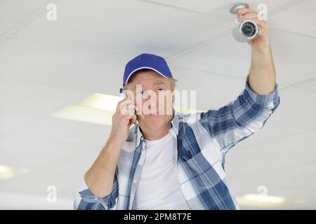 technicien installant une caméra cctv au plafond Banque D'Images