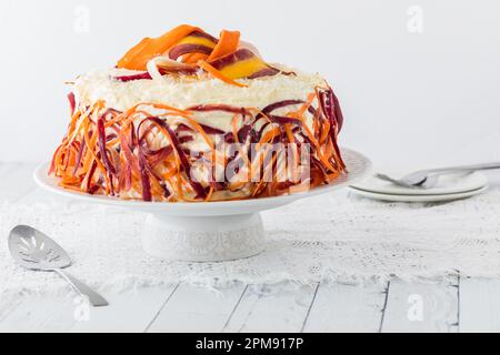 Un gâteau de carottes coloré garni de copeaux de carottes arc-en-ciel. Banque D'Images