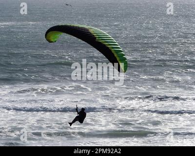 Un parapente vole au-dessus d'un océan avec Waves.Backlit silhouette Banque D'Images