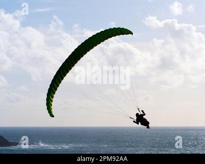 Un parapente vole au-dessus d'une scène de l'océan tournant vers sa gauche.Backlit silhouette.Sport.Loisirs Banque D'Images