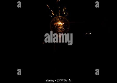 Lumière et étincelles provenant d'une lampe à incandescence qui brûle. Court-circuit. Banque D'Images