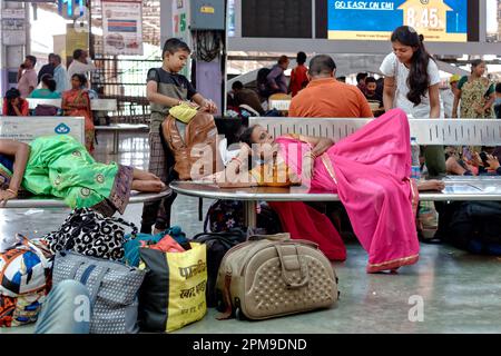 Une femme passager de chemin de fer vêtue de sari à Chhatrapati Shivaji Maharaj Terminus à Mumbai, en Inde, se reposant sur un banc en attendant son train Banque D'Images