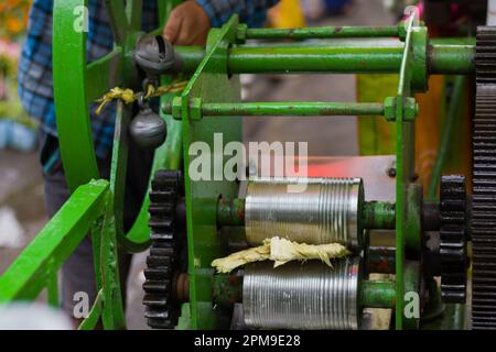 La machine à presser le jus de canne à sucre extrait le jus des bâtonnets de canne à sucre selon une méthode traditionnelle. C'est une boisson rafraîchissante très populaire en été Banque D'Images