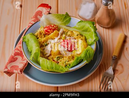 Bol de poulet oeillet et salade sur fond en bois. Banque D'Images