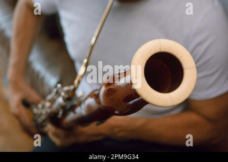 gros plan d'un homme méconnu jouant du basson à la maison, accent sur le sonnette du basson, l'espace de copie, le concept de musique Banque D'Images