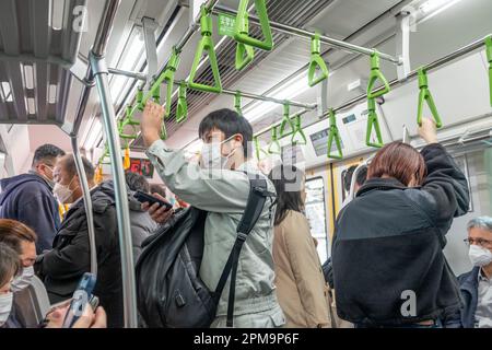 Tokyo, Japon - 16 mars 2023: Les gens qui utilisent le métro à Tokyo et tous portent des masques pour être protégés par la maladie. Personnes debout dans Metro. Banque D'Images