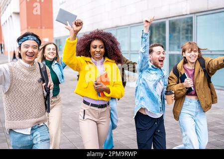 les jeunes étudiants célèbrent dans la rue la fin des examens scolaires, les expressions du bonheur et de la satisfaction, groupe multiracial de rire de l'université stude Banque D'Images