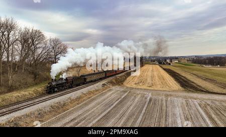 Un train noir est photographié avec de la fumée qui s'affiche dans ses deux cheminées de teinte blanche, créant ainsi une image saisissante Banque D'Images