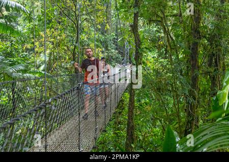 La Fortuna, Costa Rica - les touristes traversent un pont suspendu sous la pluie dans le parc Mistico Hanging Bridges. Le parc permet aux touristes de faire de la randonnée à travers le Banque D'Images