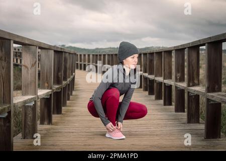 Une femme qui enjambe son cordonnet, preteration pour une course sur une promenade en bois Banque D'Images