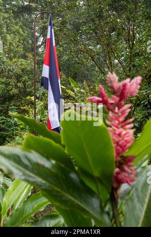 La Fortuna, Costa Rica - Un drapeau costaricain est suspendu à l'entrée du parc des ponts suspendus Mistico. Le parc permet aux touristes de marcher à travers la pluie f Banque D'Images