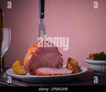 Rôti de gammon traditionnel qui a été tranché sur une assiette avec quelques légumes autour d'elle. Banque D'Images