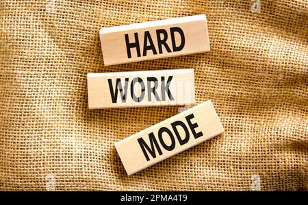 Symbole du mode travail dur. Mots-clés mode de travail dur sur bloc de bois sur un magnifique arrière-plan de toile de table de toile. Concept de mode Business et Hard Work Banque D'Images