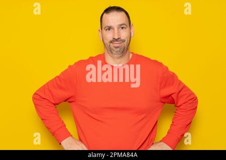 Homme à barbe gai portant un chandail rouge posé isolé sur fond gris, portrait de studio. Concept de mode de vie des personnes. Créer un espace de copie. Debout Banque D'Images