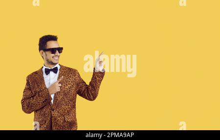 Heureux homme annonçant quelque chose et pointant du doigt vers le côté à l'arrière-plan de l'espace de copie Banque D'Images