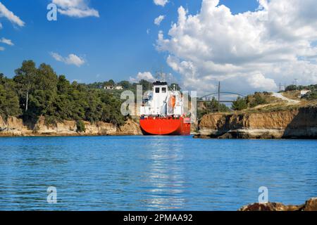 Le pétrolier navigue entre les rochers du canal de Corinthe. Paysage estival pittoresque du canal de Corinthe, par une journée ensoleillée et lumineuse, dans un ciel bleu et blanc Banque D'Images