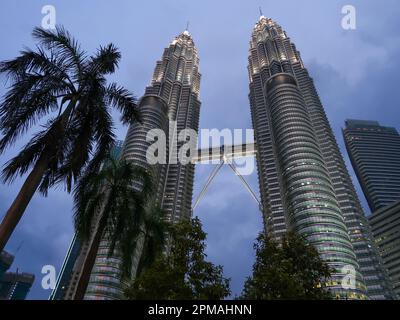 KUALA LUMPUR, MALAISIE - 10 NOVEMBRE 2015 : les tours jumelles Petronas reflètent dans l'étang dans le parc KLCC, qui est bordée d'hôtels de luxe et de shopp Banque D'Images