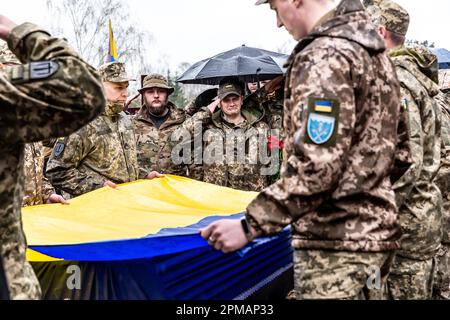 Les militaires saluent et tiennent le drapeau ukrainien par le cercueil lors des funérailles d'Evgeny Yakovlev, 42 ans, un soldat tué par les forces russes sur le front ukrainien oriental dans un combat, sur le cimetière de Lisove à Kiev, la capitale de l'Ukraine sur 12 avril 2023. Le cimetière de Lisove est où la plupart des militaires tombés de Kiev sont enterrés. Comme l'invasion à grande échelle de l'Ukraine par les forces russes continue, la lutte dans l'est de l'Ukraine provoque un taux de victimes très élevé, bien que les chiffres exacts soient inconnus. L'Ukraine se prépare à une offensive de printemps pour reprendre les terres occupées par la Russie. (Photo par Dominika Zarzycka Banque D'Images