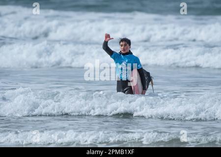 Un jeune surfeur mâle transportant son surf et faisant des vagues et marchant hors de la mer après avoir concouté au concours de surf RIP Curl Grom Search sur Fi Banque D'Images