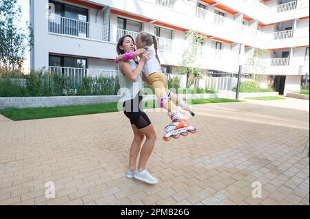 Mère tenant sa fille dans des patins à roulettes. Banque D'Images