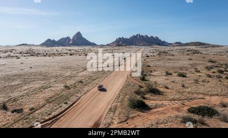 Une vue aérienne d'une voiture voyageant le long d'une route de sable dans le désert du Namib. Banque D'Images