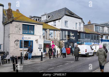 Les gens qui marchent devant les magasins et les restaurants sur le quai dans un froid St Ives en Cornouailles en Angleterre au Royaume-Uni. Banque D'Images