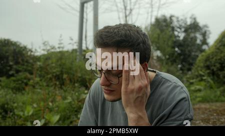Beau homme avec des lunettes writhes dans la douleur, luttant un début soudain de problèmes de santé Banque D'Images