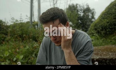 Homme avec des lunettes writhes dans la douleur, luttant un début soudain de problèmes de santé Banque D'Images