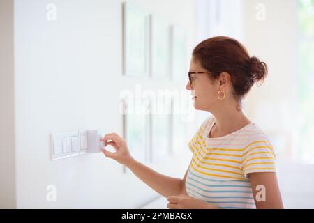 Femme réglant le thermostat. Chauffage central. Température intérieure confortable. Régulateur de climatisation de salle à réglage femelle. Rafraîchi par temps chaud en été. Banque D'Images