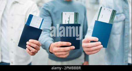 Trois hommes méconnaissables montrant des passeports avec cartes d'embarquement, gros plan Banque D'Images